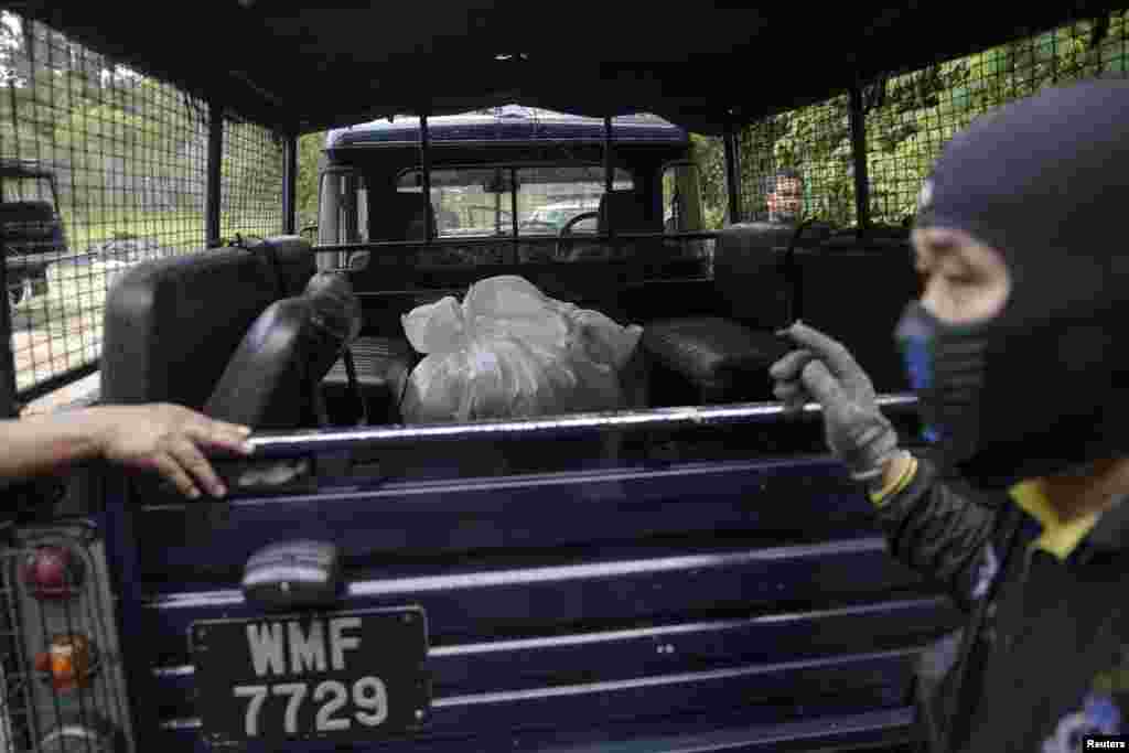 Tim forensik polisi mengangkut kantung jenazah berisi sisa-sisa mayat manusia yang digali dari kuburan dekat kamp perdagangan manusia yang ditelantarkan di hutan dekat perbatasan Thailand di Bukit Wang Burma, Malaysia utara (27/5). ​(Reuters/Damir Sagolj)