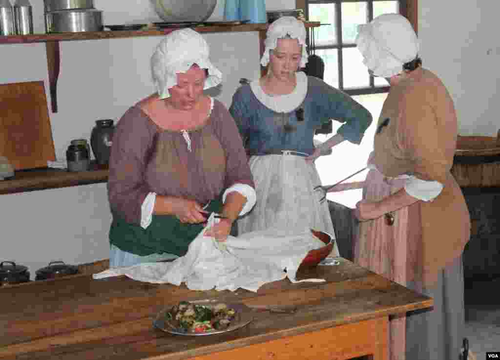Para perempuan memasak di dapur di Colonial Williamsburg, dimana seorang perempuan terhormat tidak akan pernah memperlihatkan sikunya, sepanas apapun udara. 