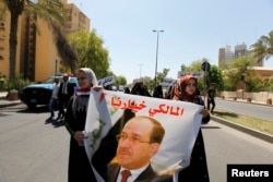 Iraqis carry portraits of incumbent Iraqi Prime Minister Nuri al-Maliki as they gather in support of him in Baghdad August 13, 2014. Maliki said on Wednesday the appointment of Haider al-Abadi to replace him was a "violation" of the law.