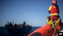 Migrants from Eritrea, Egypt, Syria and Sudan, are assisted by aid workers of the Spanish NGO Open Arms, after fleeing Libya on board a precarious wooden boat in the Mediterranean sea, about 110 miles north of Libya, on Jan. 2, 2021. 