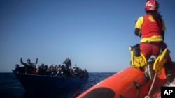 Des migrants sont aidés par des travailleurs humanitaires de l'ONG espagnole Open Arms, après avoir fui la Libye à bord d'une embarcation précaire en mer Méditerranée, à environ 110 miles au nord de la Libye, le 2 janvier 2021.