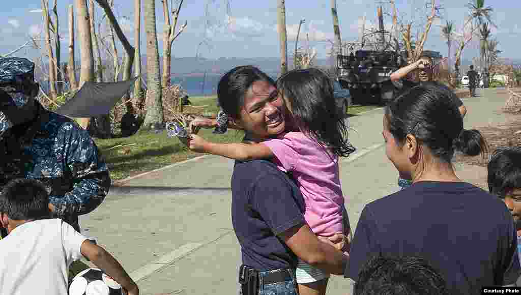 A member of the U.S. Navy hugs a child during a visit to Philippine Army base Camp Downes in support of Operation Damayan, Nov. 18, 2013. (U.S. Navy)