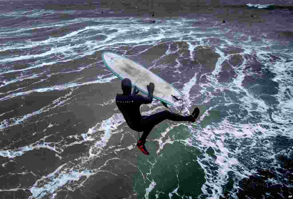 A surfer jumps into the storm-beaten Baltic Sea from the pier in Timmendorfer Strand, Germany, as temperatures reached 2&deg; C.