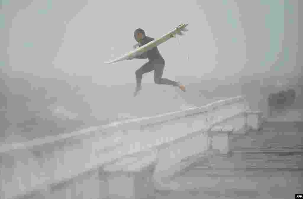 A surfer jumps off the pier into Port Phillip Bay to take advantage of the waves as a storm lashes the Melbourne area, Japan.