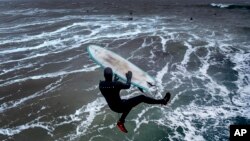 A surfer jumps into the storm-beaten Baltic Sea from the pier in Timmendorfer Strand, Germany, as temperatures reached 2&deg; C.