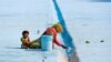 A woman paints the floor of a pool as her child pulls at her saree in Delhi, India.