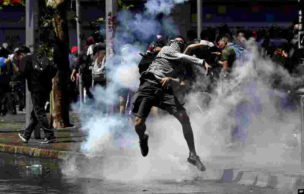 Un manifestante devuelve un bote de gas lacrimógeno a la policía durante los enfrentamientos en Santiago, Chile, el lunes 21 de octubre de 2019. (Foto AP / Miguel Arenas).