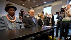 FILE - Friends of the Earth campaign leader Geert Ritsema, second left, and plaintiff Eric Dooh, left, wait for the start of the ruling in the court case of Nigerian farmers against Shell, in The Hague, Netherlands, Jan. 30, 2013. 