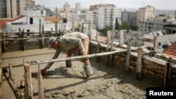 A Palestinian worker flattens cement on the roof of a building under construction in Gaza City, Sept. 22, 2013.