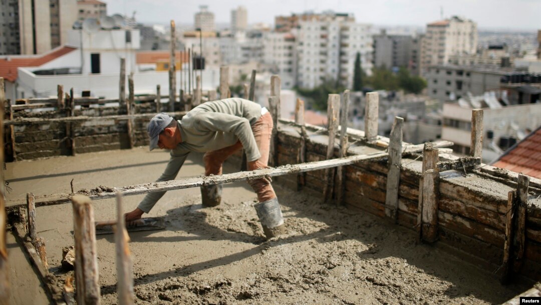 A Palestinian worker flattens cement on the roof of a building under construction in Gaza City, Sept. 22, 2013.