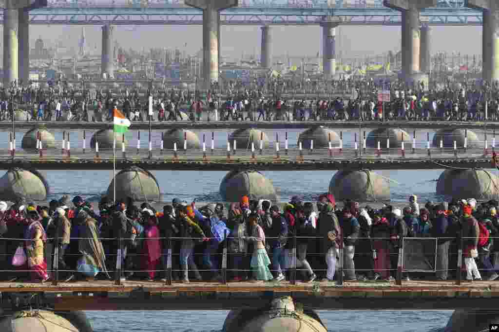 Hindu devotees cross pontoon bridges as they arrive for bathing at the confluence of the Ganges, the Yamuna, and the Saraswati rivers during the 45-day-long Maha Kumbh festival in Prayagraj, India.