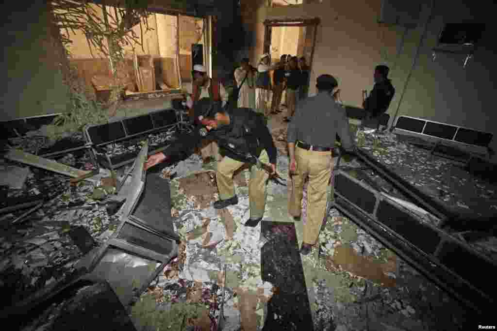 Security officials inspect the site of bomb blast in a judicial compound in Peshawar, Pakistan, March 18, 2013.
