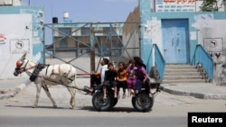Palestinian children ride a donkey cart past a U.N. food distribution center in Khan Younis refugee camp, southern Gaza Strip, April 5, 2013.