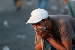 An anti-government protester reacts to tear gas fired by security forces during a demonstration in Baghdad, Iraq, Oct. 3, 2019.