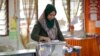 FILE-A woman casts her vote during the by-election at a polling station in the southern coastal town of Port Dickson.