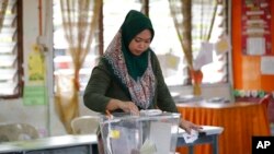 FILE-A woman casts her vote during the by-election at a polling station in the southern coastal town of Port Dickson.