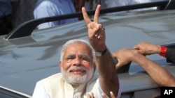 India's main opposition Bharatiya Janata Party’s prime ministerial candidate Narendra Modi displays the victory symbol to supporters after casting his vote in Ahmadabad, India, April 30, 2014. 