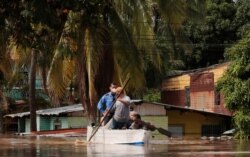 Residents paddle a boat through a flooded street in the aftermath of Hurricane Eta in Planeta, Honduras, Nov. 5, 2020.
