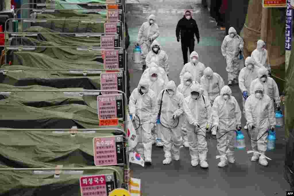 Workers wearing protective gear spray disinfectant at a market in the southeastern city of Daegu, South Korea, as a preventive measure after the COVID-19 coronavirus outbreak. South Korea reported two additional deaths from coronavirus and 123 more cases.