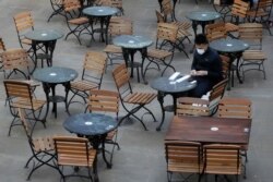 FILE - A man sits in an empty cafe in London, Sept. 24, 2020.