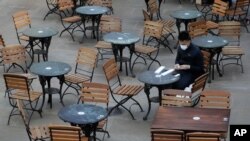 A man sits in an empty cafe in London, Sept. 24, 2020, after Britain's Prime Minister Boris Johnson announced a range of new restrictions to combat the rise in coronavirus cases in England.