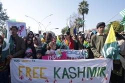 People carry signs and flags as they walk to mark Kashmir Solidarity Day, in Islamabad, Pakistan Feb. 5, 2020.