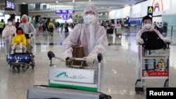 Penumpang mengenakan APD di tengah merebaknya pandemi COVID-19 di Bandara Internasional Hong Kong, Hong Kong, China 17 Maret 2020. (REUTERS/Tyrone Siu)
