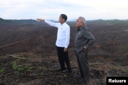 Presiden Joko Widodo memberi isyarat saat Gubernur Kalimantan Timur Isran Noor berdiri di distrik Sepaku di Kabupaten Penajam Paser Utara, Kalimantan Timur. (Foto: Antara/Akbar Nugroho Gumay via REUTERS)