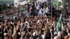 FILE - Supporters of the Tehreek-e-Labbaik Pakistan (TLP) Islamist political party raise their hands as they listen to the speech of their leader during a protest march to condemn a cartoon competition by the Netherlands, in Lahore, Pakistan, Aug. 29, 2018. 