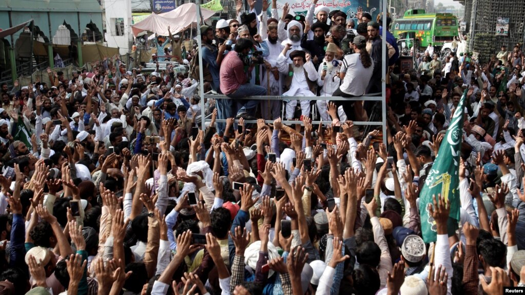 FILE - Supporters of the Tehreek-e-Labbaik Pakistan (TLP) Islamist political party raise their hands as they listen to the speech of their leader during a protest march to condemn a cartoon competition by the Netherlands, in Lahore, Pakistan, Aug. 29, 2018.