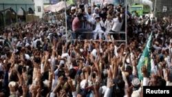 FILE - Supporters of the Tehreek-e-Labbaik Pakistan (TLP) Islamist political party raise their hands as they listen to the speech of their leader during a protest march to condemn a cartoon competition by the Netherlands, in Lahore, Pakistan, Aug. 29, 2018. 