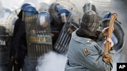 A demonstrator wearing a stolen Guardia di Finanza jacket throws a metal pole at the Guardia di Finanza during anti-government clashes near the parliament in Rome, 14 Dec 2010.