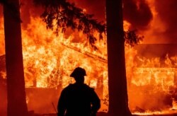 Firefighters attempt to get control of the scene as dozens of homes burn during the Dixie Fire in the Indian Falls neighborhood of unincorporated Plumas County, California, on July 24, 2021.