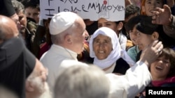 FILE - Pope Francis greets migrants and refugees at Moria refugee camp near the port of Mytilene, on the Greek island of Lesbos, April 16, 2016. 