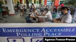 FILE - People and officials take part in a mock voting exercise held by the local government ahead of the country's 2022 national elections, at a school in Manila on Oct. 23, 2021. 