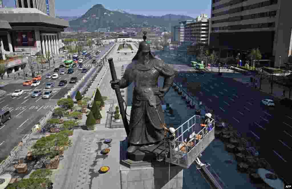 A South Korean worker washes the bronze statue of Admiral Yi Sun-Shin, who won a major naval victory over Japan in the 16th century, during a street and park clean-up event for spring at Gwanghwamun square in Seoul.