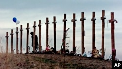 Seorang wanita berdiri di antara salib yang dipasang di sebuah bukit di atas SMA Columbine di Littleton, Colorado, untuk mengenang mereka yang tewas dalam penembakan di sekolah pada tanggal 20 April 1999 (AP)