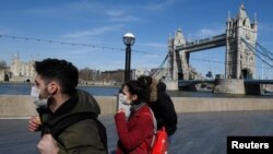 រូបឯកសារ៖ មនុស្ស​ពាក់ម៉ាស់ ដើរ​នៅ​ក្បែរ​ស្ពាន Tower Bridge ក្នុង​ពេល​មាន​ការរាតត្បាត​នៃ​ជំងឺ​កូវីដ១៩ នៅតែ​បន្ត​នៅ​ទីក្រុង​ឡុងដ៍ នៃ​ប្រទេស​អង់គ្លេស កាលពី​ថ្ងៃទី២៣ ខែមីនា ឆ្នាំ២០២០។