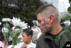 Un hombre con el nombre de un cadete de policía muerto en un ataque con coche bomba escrito en la cara, participa en una marcha para repudiar el terrorismo. Bogotá, Colombia, enero 20 de 2019.