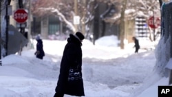 Orang-orang berjalan di jalan yang tertimbun salju setelah badai salju di Chicago, Selasa, 16 Februari 2021. 