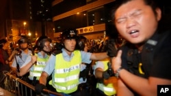 A pro-democracy protester is struck by a baton as riot police move on an occupied section of a roadway in the Mong Kok district of Hong Kong, Oct. 18, 2014. 