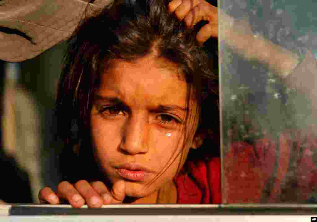 A Syrian girl, newly displaced by the Turkish military operation in northeastern Syria, cries as she sits in a bus upon her arrival at the Bardarash camp, north of Mosul, Iraq. 