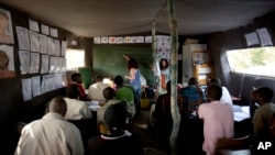 In this Aug. 7, 2015, photo, volunteer teacher Delphine Blain teaches French to immigrants at a makeshift school set at camp near Calais, northern France. 