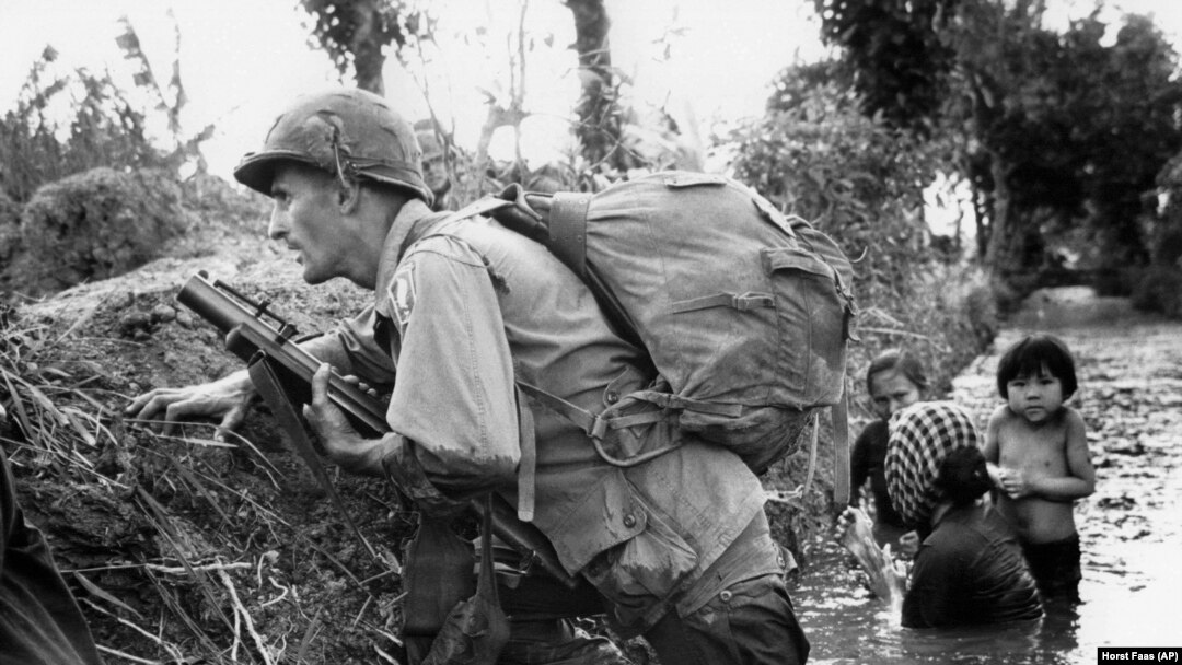 Tư liệu: Ảnh chụp ngày 1/1/1966. Một quân nhân thuộc Lữ đoàn 173 Nhảy dù trú đạn cùng nhiều phụ nữ và trẻ em trong thời chiến tranh VN. (AP Photo/Horst Faas, File)