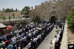 Palestinians pray outside the Lion's Gate in Jerusalem's Old City, July 18, 2017. A dispute over metal detectors has escalated into a new showdown between Israel and the Muslim world over a contested Jerusalem shrine.