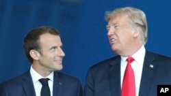 U.S. President Donald Trump speaks with French President Emmanuel Macron as they walk in the atrium during a summit of NATO heads of state and government at NATO headquarters in Brussels, July 11, 2018.