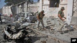 Foreign security officers inspect wreckage at the scene of a suicide car bomb attack that targeted a United Nations convoy, outside the airport in Mogadishu, Somalia, Dec. 3, 2014.