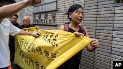 FILE - Members of League of Social Democrats hold banner outside the West Kowloon Magistrates' Courts in Hong Kong, May 30, 2024, ahead of verdicts in national security case. The banner reads "Exercising Constitutional rights is not a crime."