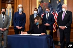 House Speaker Nancy Pelosi of California signs the article of impeachment against President Donald Trump in an engrossment ceremony before transmission to the Senate for trial on Capitol Hill, in Washington, Jan. 13, 2021.