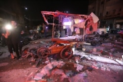 FILE - People gather at the site of an air strike on a market in the town of Maarat al-Numan, Syria, on May 21, 2019.